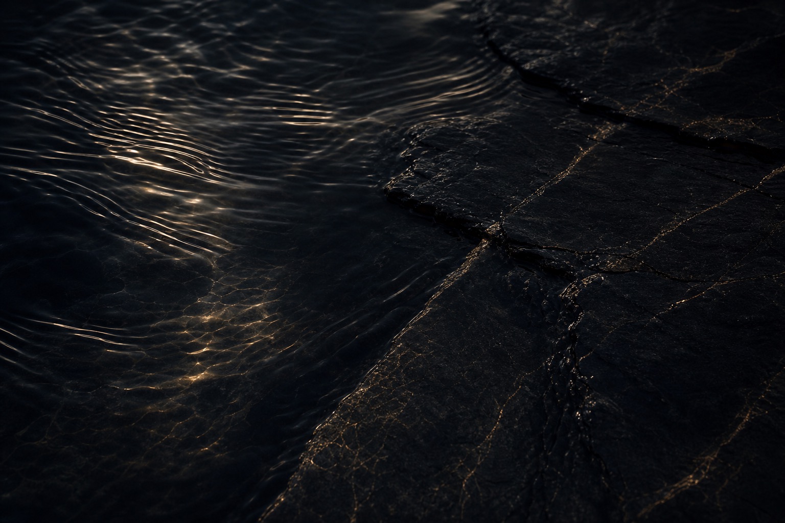 Reflexos de luz sobre água escura e pedra negra, evocando a atmosfera da marca